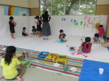 室内全体に大きな画用紙が貼られ子供たちが好きな絵を描いている写真