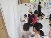 お母さんが見守る中小さな子供が壁に落書きを楽しんでいる写真