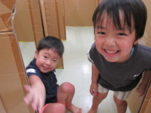段ボールの入り口で男の子2人が笑顔でカメラを見ている写真
