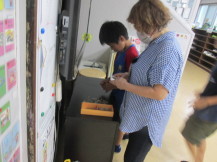 関係者と子どもがテーブルの前でクリップつなぎに集中している写真