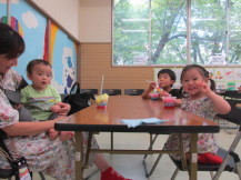 テーブルにかき氷を置いてカメラに向かってポーズを取っている4人の子どもと保護者の写真