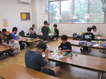 複数並べられた長テーブルの上で2人対戦でそれぞれカードゲームを行っている子どもたちの写真