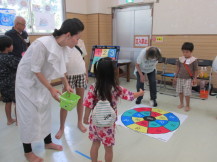 床に設置された丸い的目がけて子どもたちがお手玉だーつをしている写真