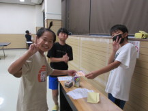 予選を勝ち抜いた子どもが、ピースサインをしながら決勝戦チケットを受け取っている写真