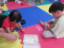 小さな子どもたちが、紙のかぼちゃに小さなシールを貼っている写真