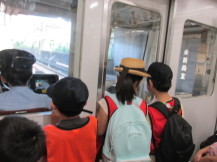 電車に乗って、運転席を覗いている子供たちの写真