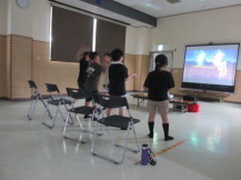 正面のモニターに映し出された映像を見ながらゲームを楽しんでいる子供達を後方から写した写真