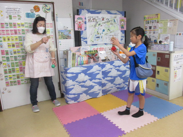 玄関前のロビーでスタッフともにけん玉に挑戦する小学生の写真