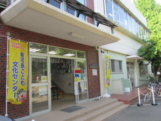 玄関の扉を開放し、向かって右側にかわさき市民活動センターと縦にかかれた旗、左側に南河原こども文化センターと縦にかかれた旗が置いてあり、扉にはバルーンで作られたこいのぼりが飾られた写真
