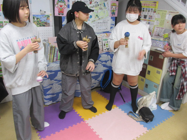 玄関ロビーでけん玉に挑戦する中学生3人