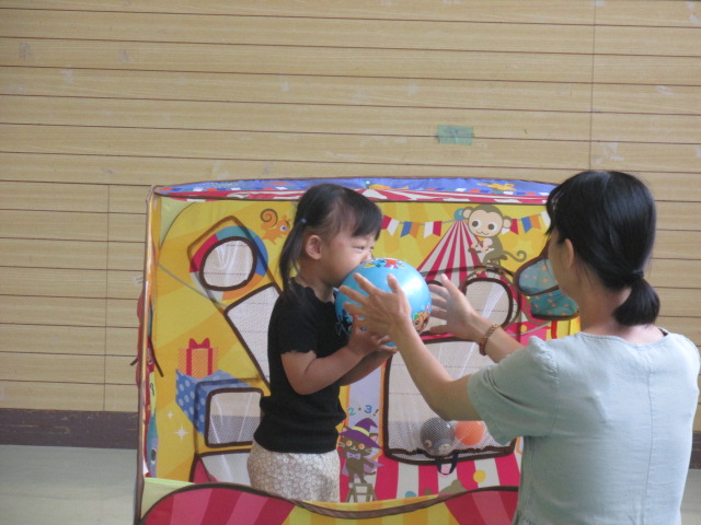 ボールプールに入って遊ぶ幼児の女の子と一緒に遊ぶお母さんの写真
