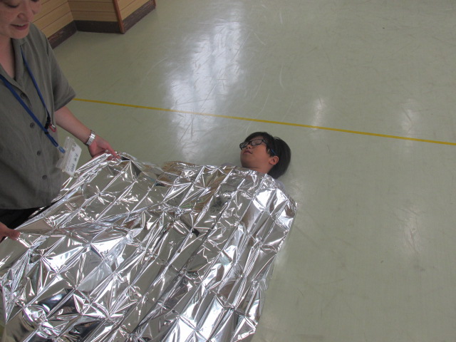 アルミシートをかけて横になっている写真