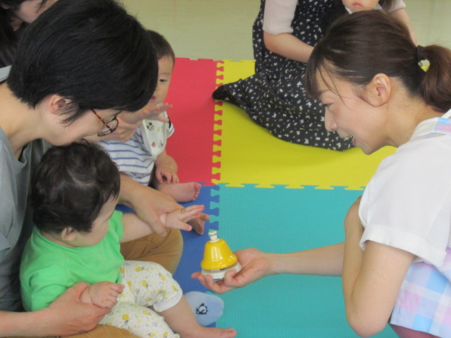 幼児が音が鳴るベルにタッチしている写真