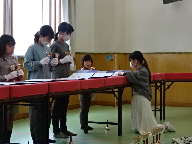 「幸ハッピーベルクラブ」でベルを練習する風景。初体験の1年生に中学生の先輩が教えている。