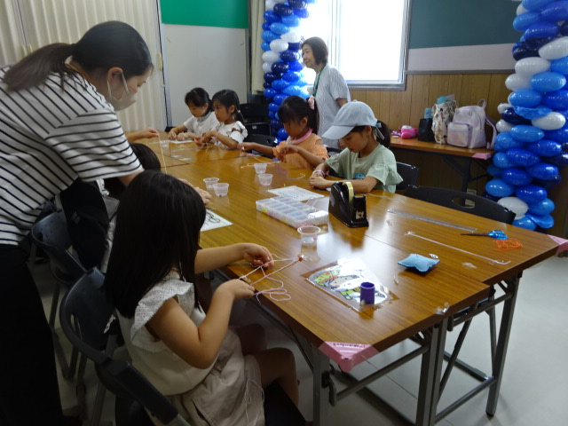「編み紐ストラップ作り」、小学生の参加者が編み紐工作に挑戦している写真