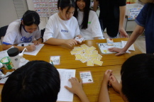 トランプを選ぶ女の子と机を囲んで勉強する4人の女の子の写真