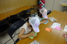 キャップを被った2人の女の子がメッセージを書いている写真