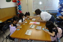 黙々とカードを作る女の子と作り方を教える講師の写真