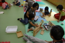 各々好きなおもちゃで遊ぶ幼児親子たちを撮影している写真