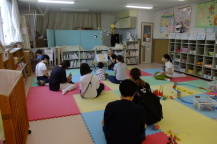 ボランティアの方の読み聞かせを座って聞いている親子たちの写真