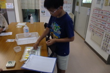 子どもが長テーブルに置かれ沢山のクリップを手に取っている様子の写真