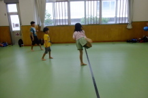 室内につけられた黒い線を越えないように子どもがボールを投げている様子の写真