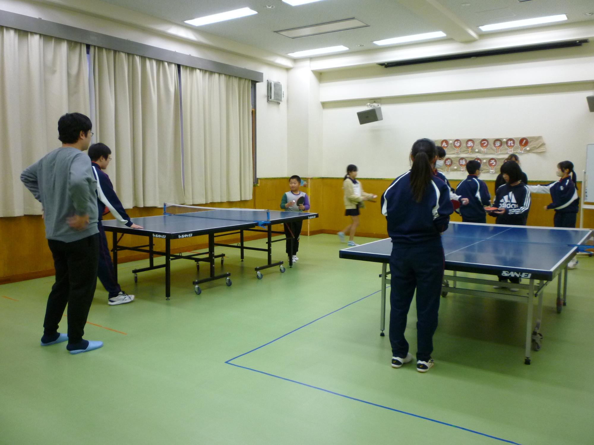 中学生に小学生が卓球を教えてもらっている様子