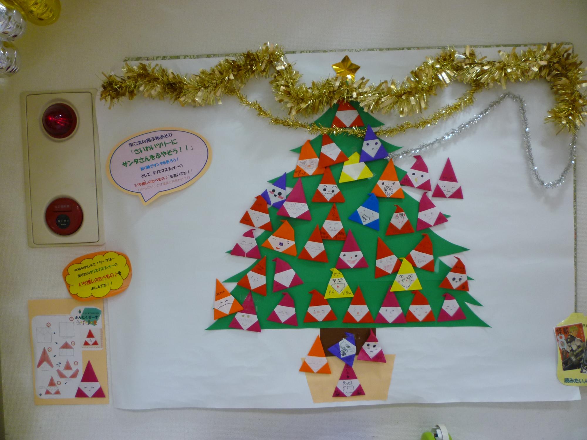 ツリーの壁面におりがみのサンタクロースが貼り付けられている様子