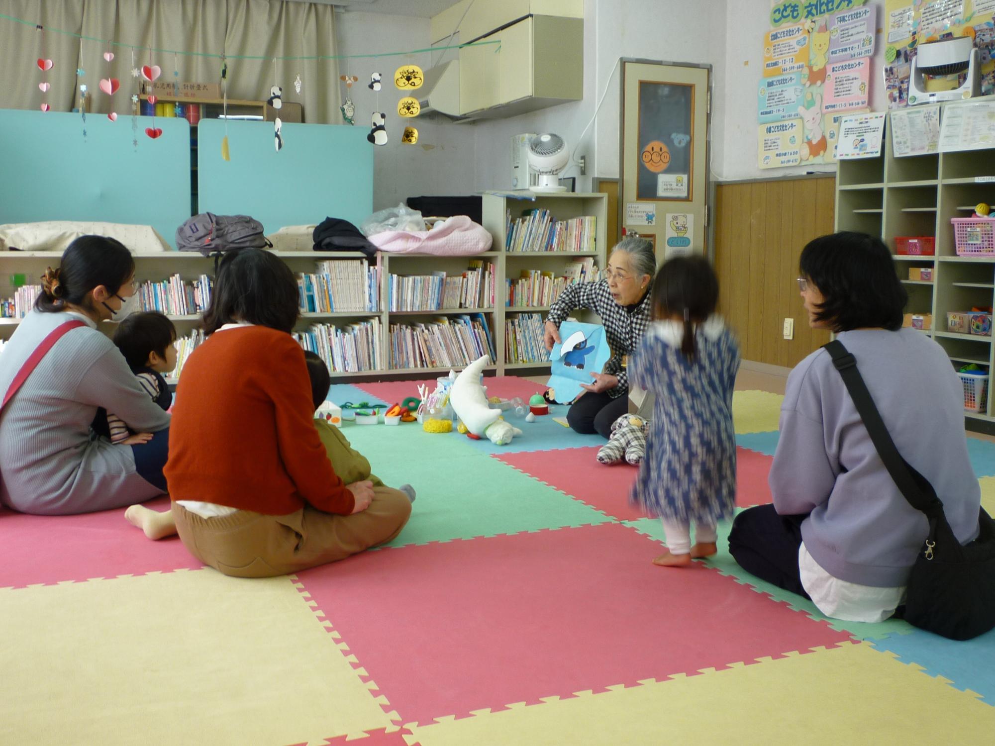 読み聞かせを聞く参加者親子の後ろ姿の写真