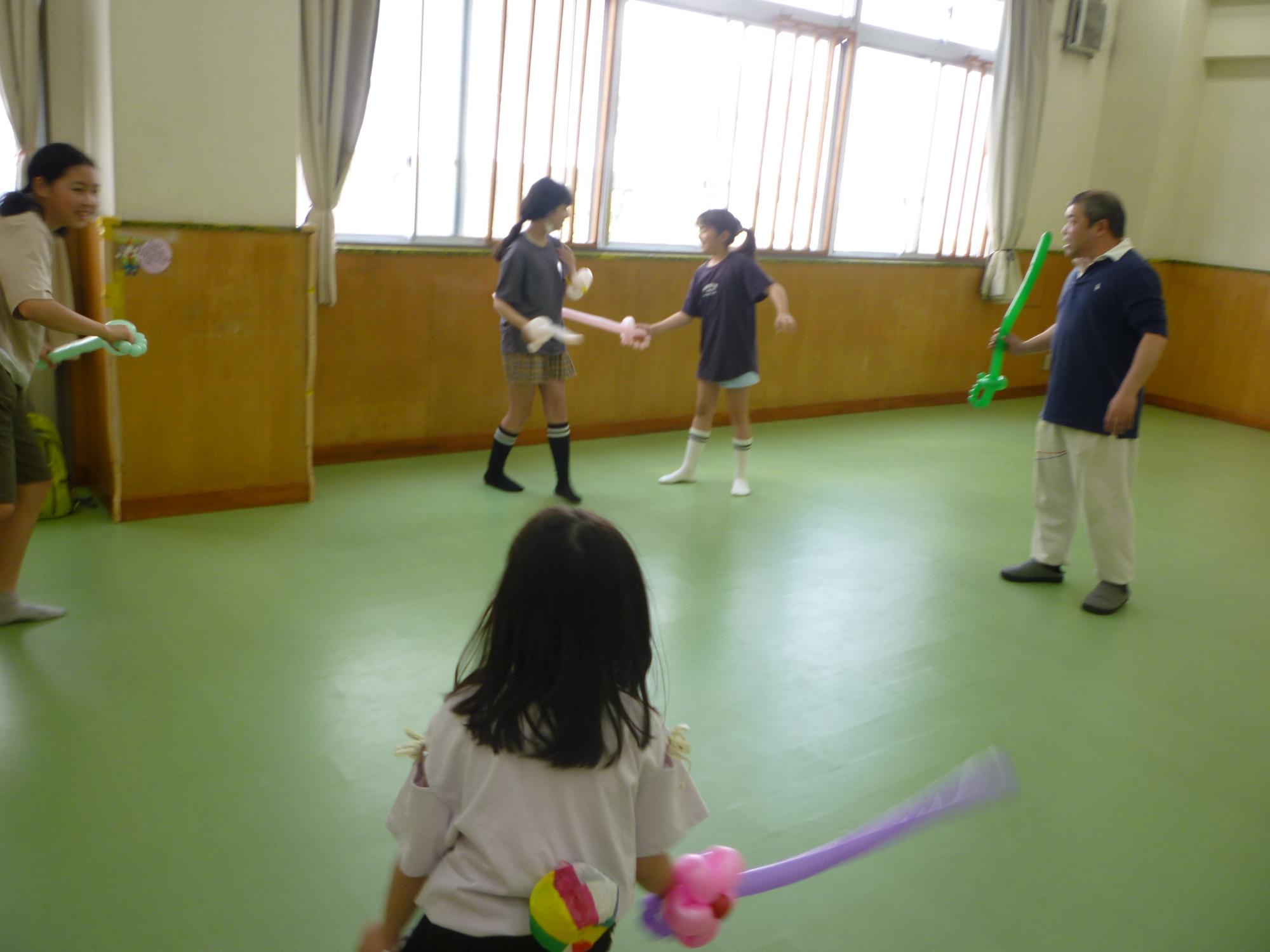 バルーンの刀で遊んでいるこどもたちの写真