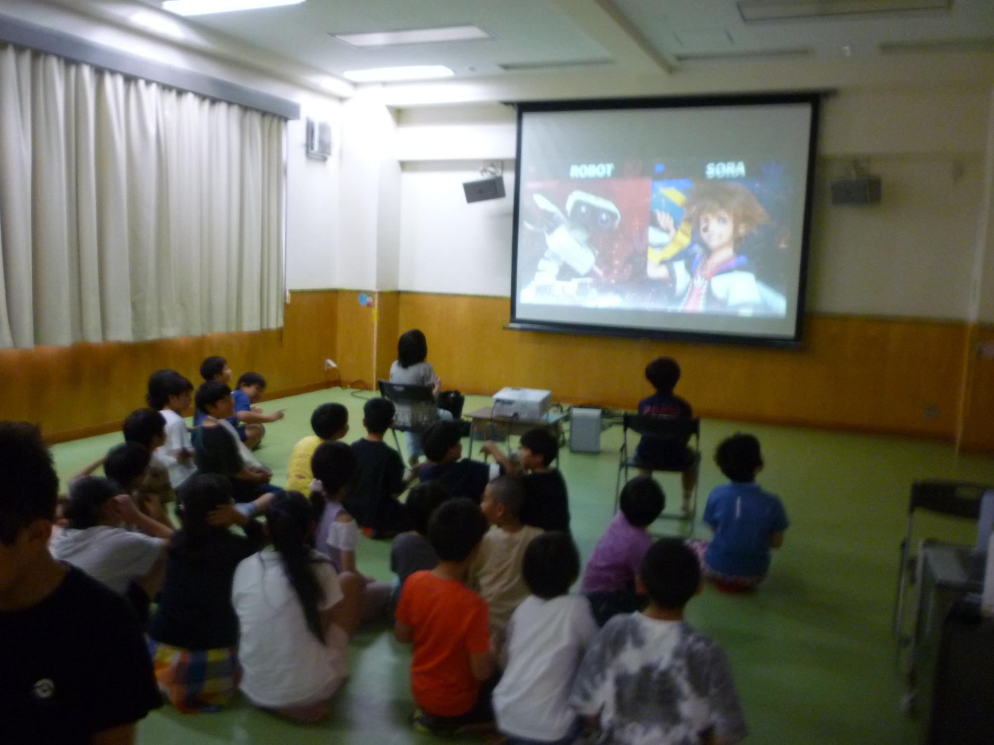 大画面のゲームをみつめるこどもたちの写真