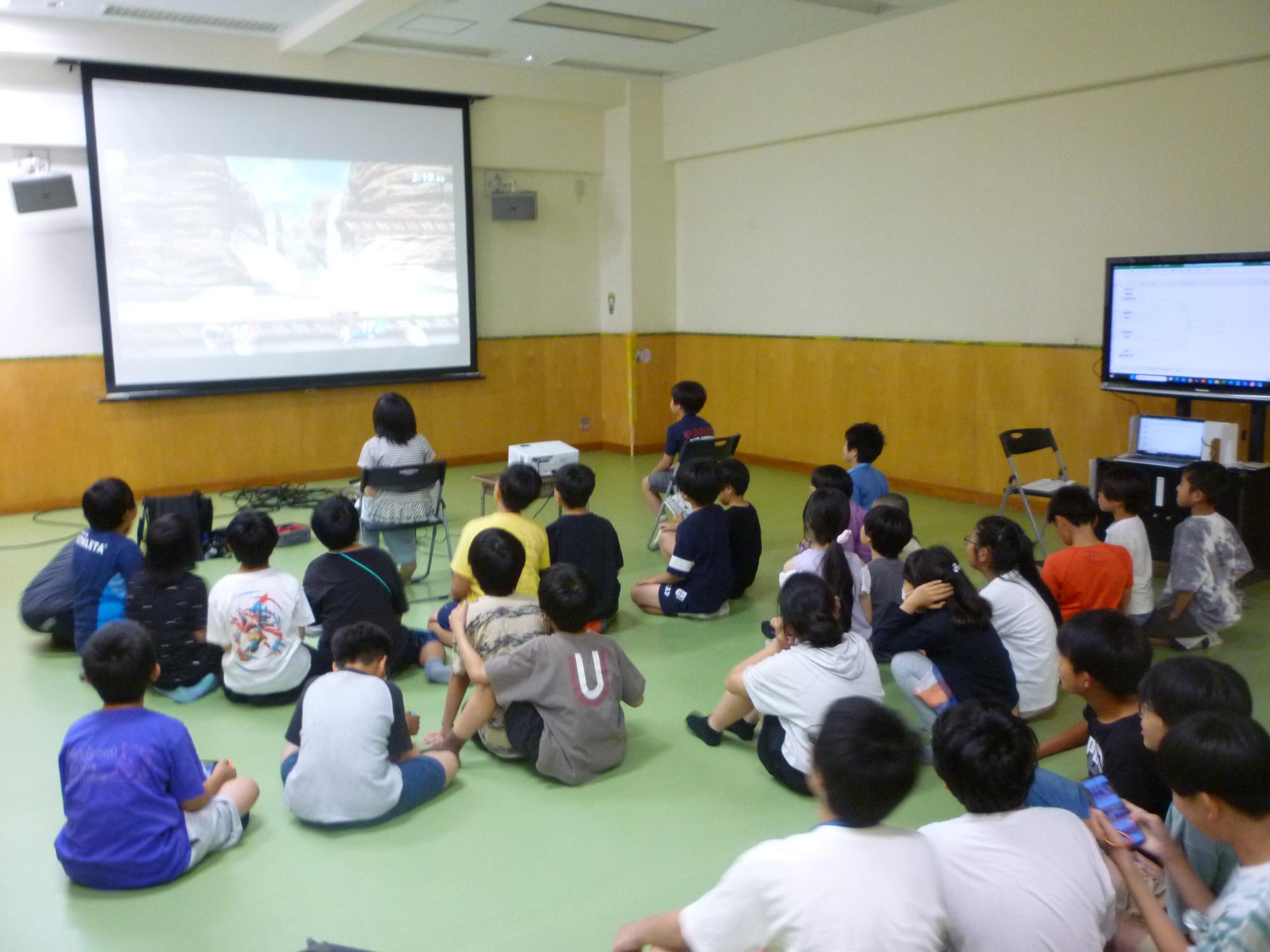 大画面のゲームをみつめるこどもたちの写真