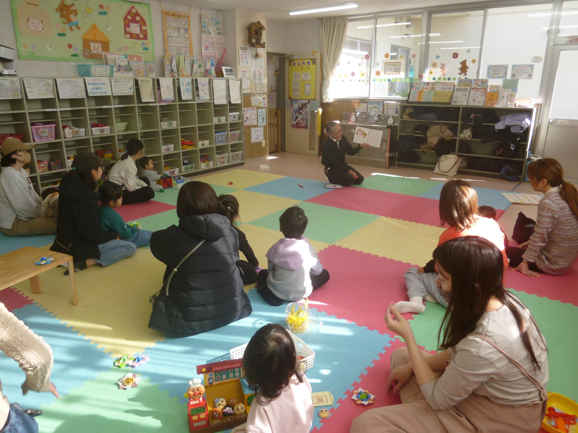 読み聞かせを聞いている幼児親子の写真