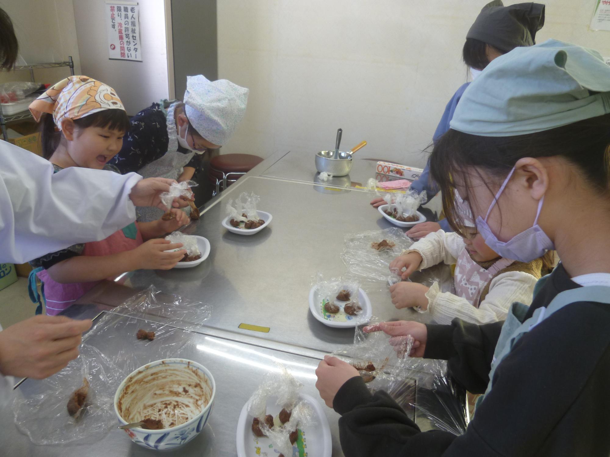 生地をラップを使って丸く成型する子どもの写真