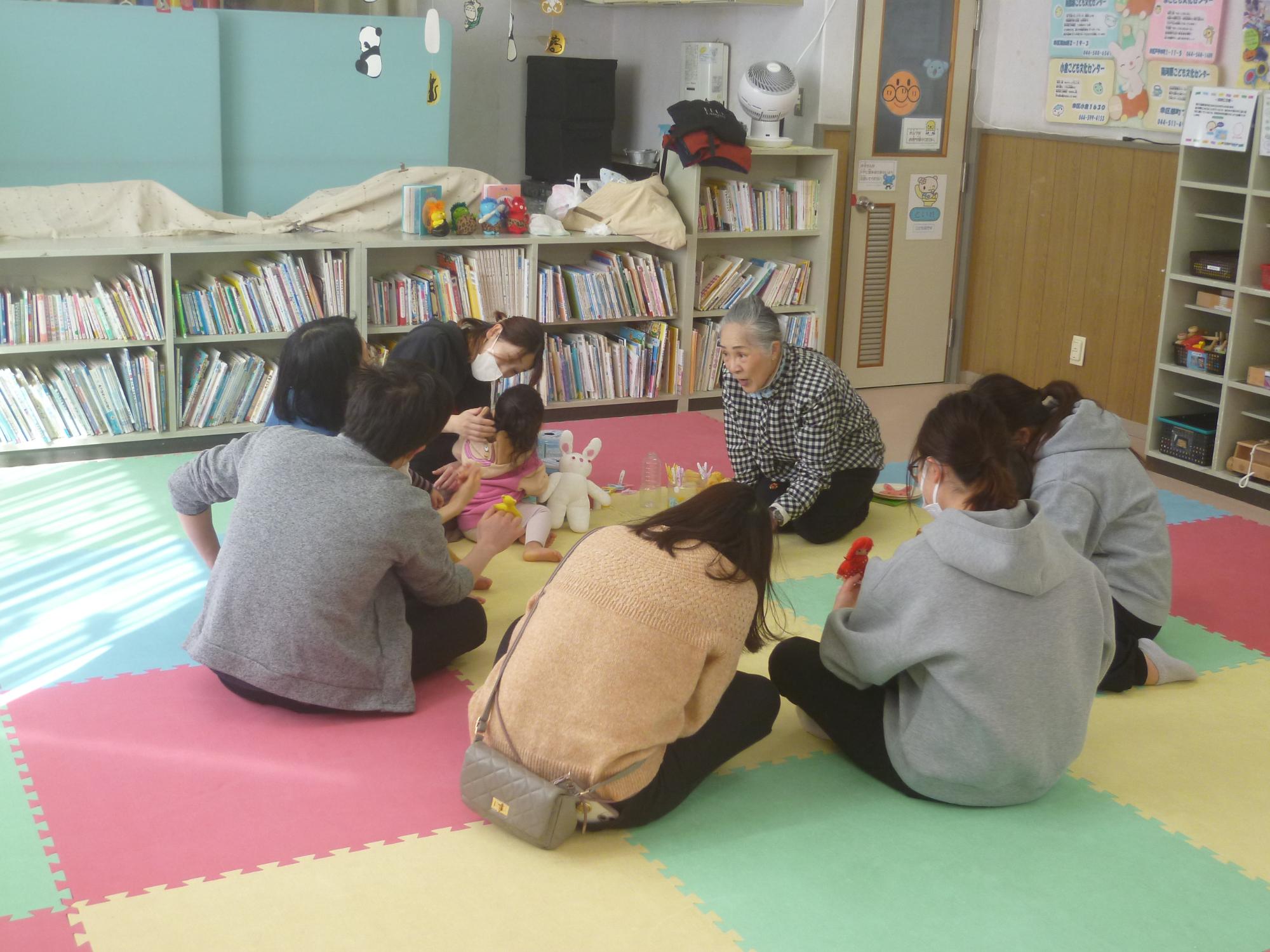 読み聞かせを聞く参加者親子の後ろ姿の写真