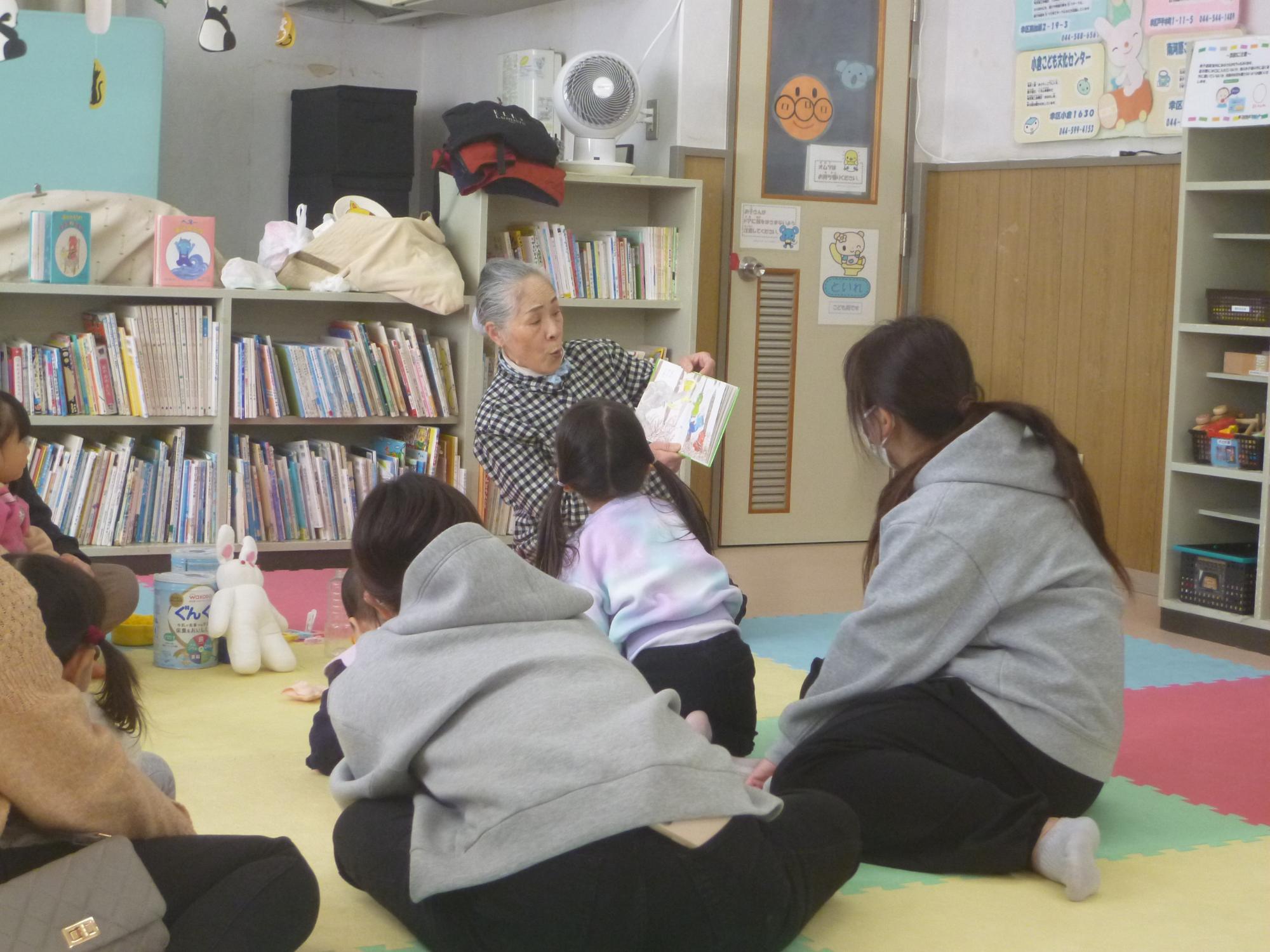 身を乗り出して読み聞かせに聞き入る子どもとそれを見守る保護者の写真