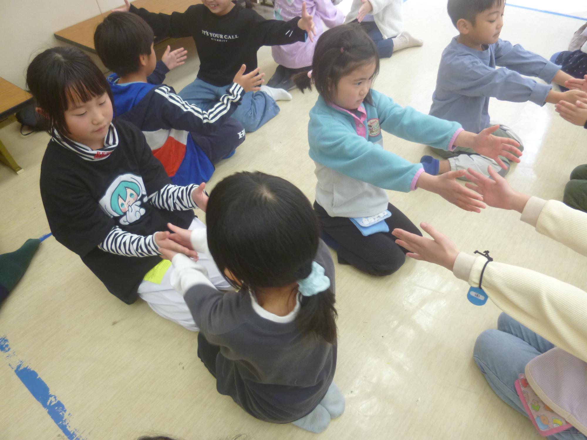 手を前に伸ばし、タイミングよく動かすレクリエーションをしている子どもたちの写真