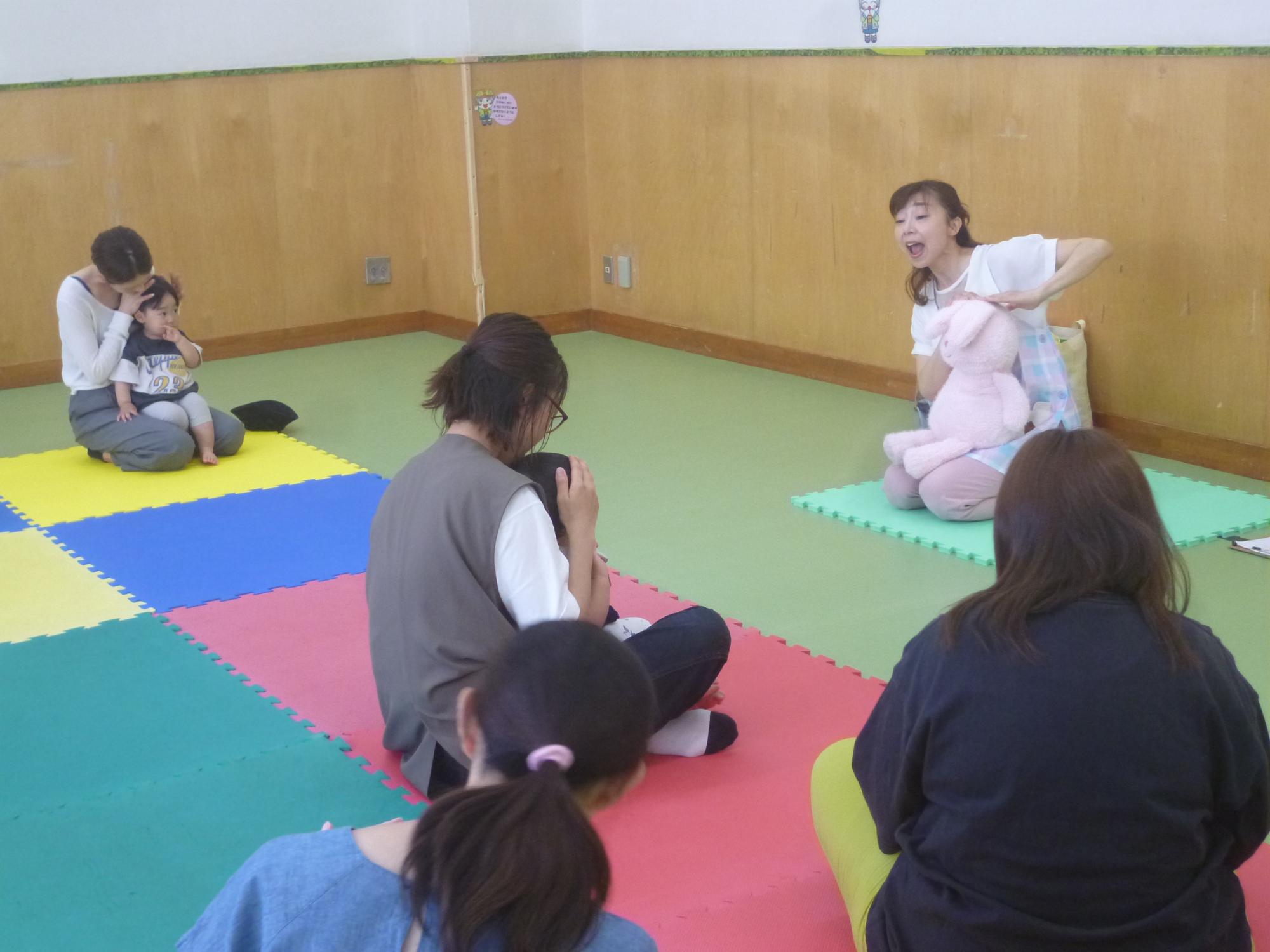 「親子リトミック」の参加親子が講師の歌に合わせて、身体を動かしている写真