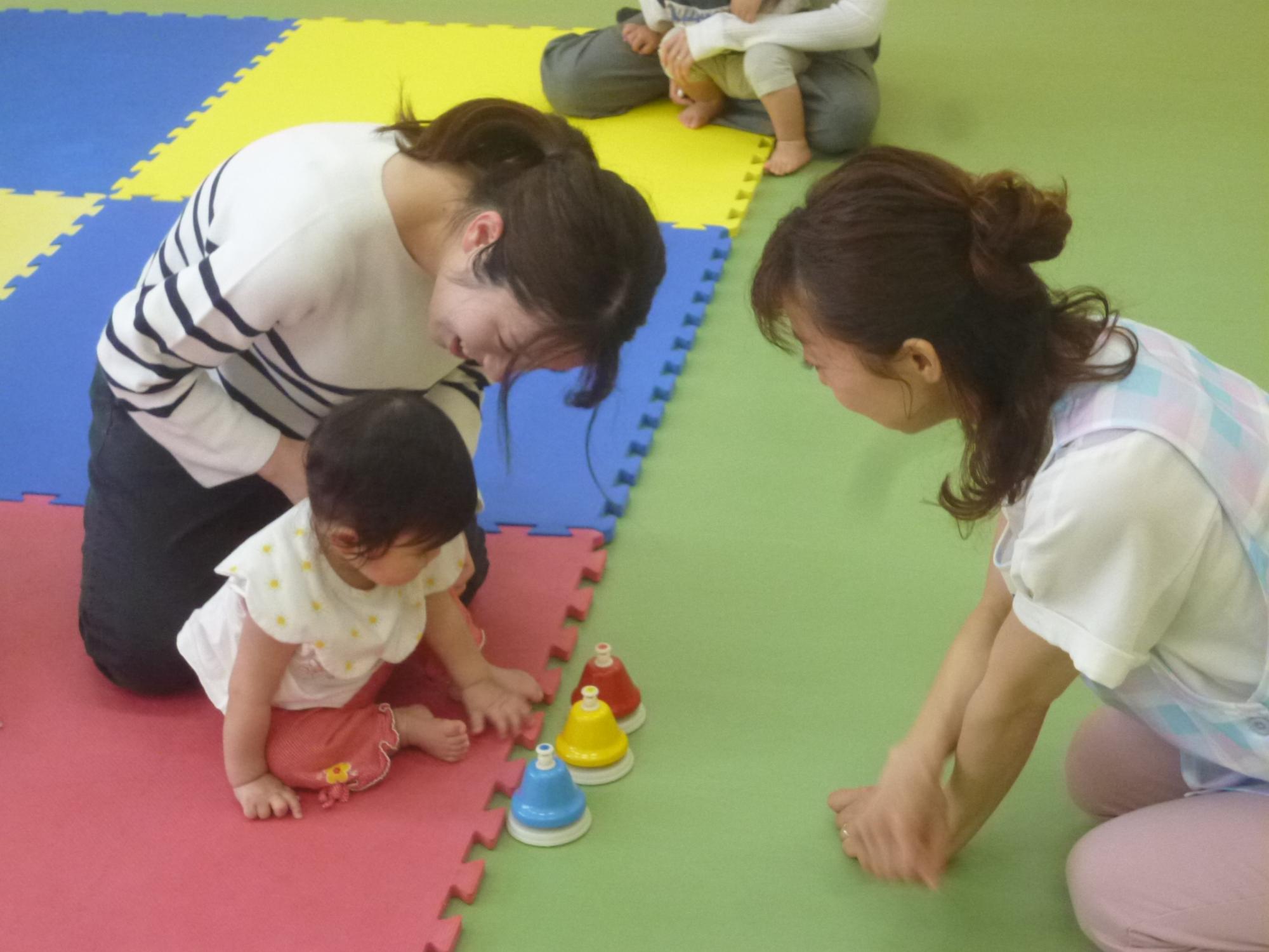 「親子リトミック」幼児が押すと音が鳴るベルを体験している写真