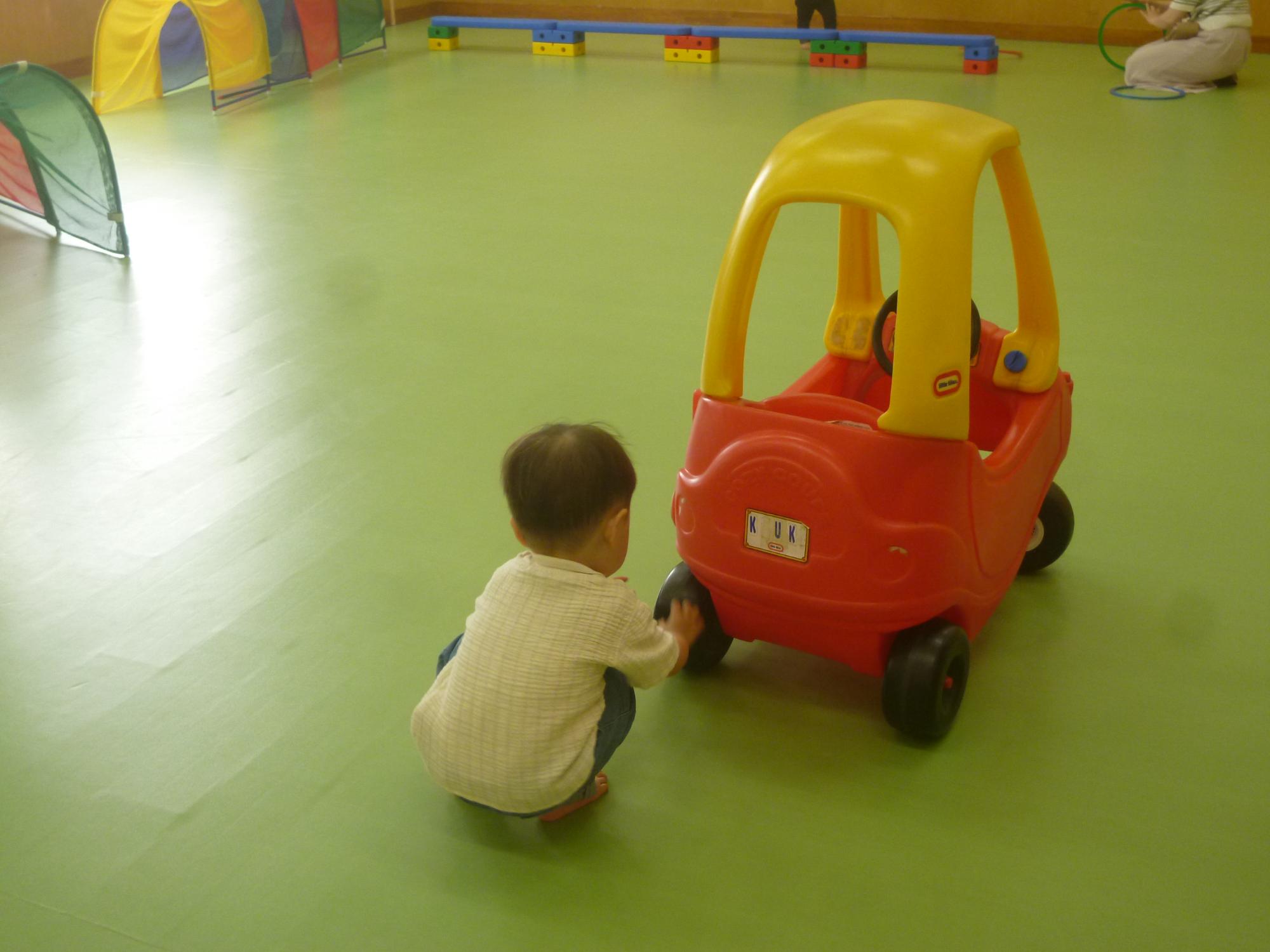 「読み聞かせ＆ちびっこぶんぶん広場」、集会室で車のおもちゃで遊ぶ幼児の写真
