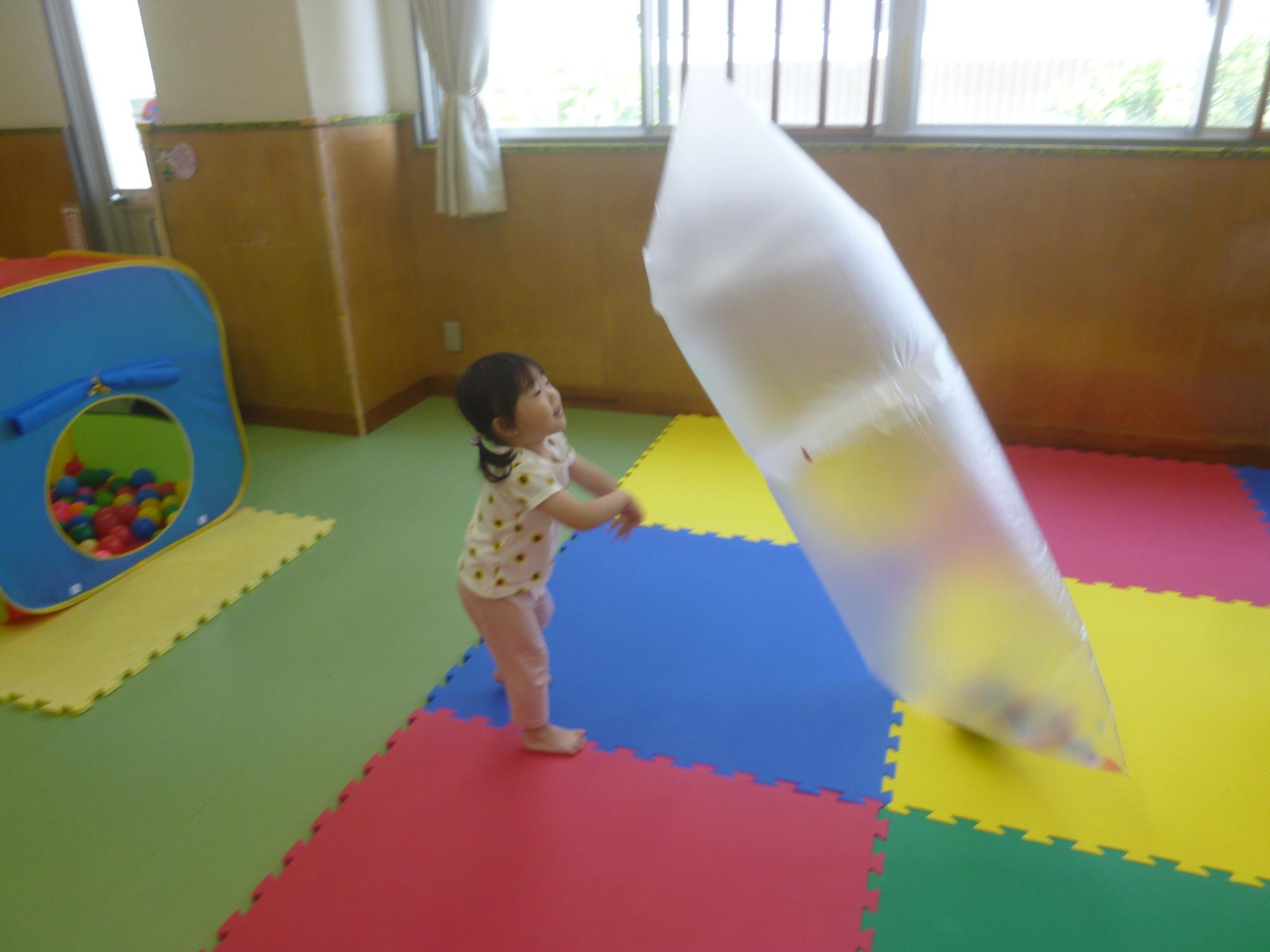 「読み聞かせ＆ちびっこぶんぶん広場」、バルーンで遊ぶ幼児の写真