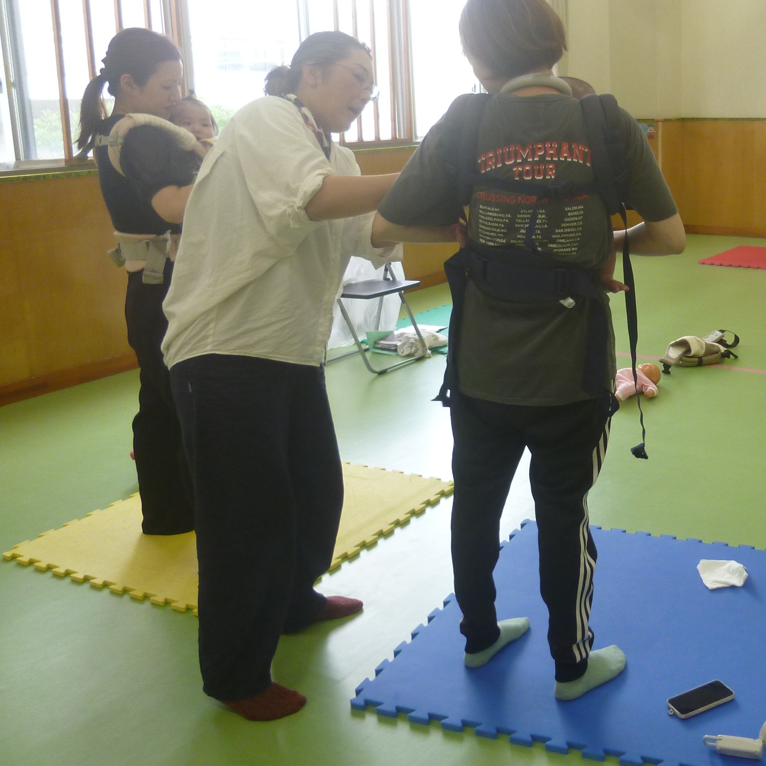 「だっことおんぶの話」、だっこひもの使い方を指導している講師と受講者の写真