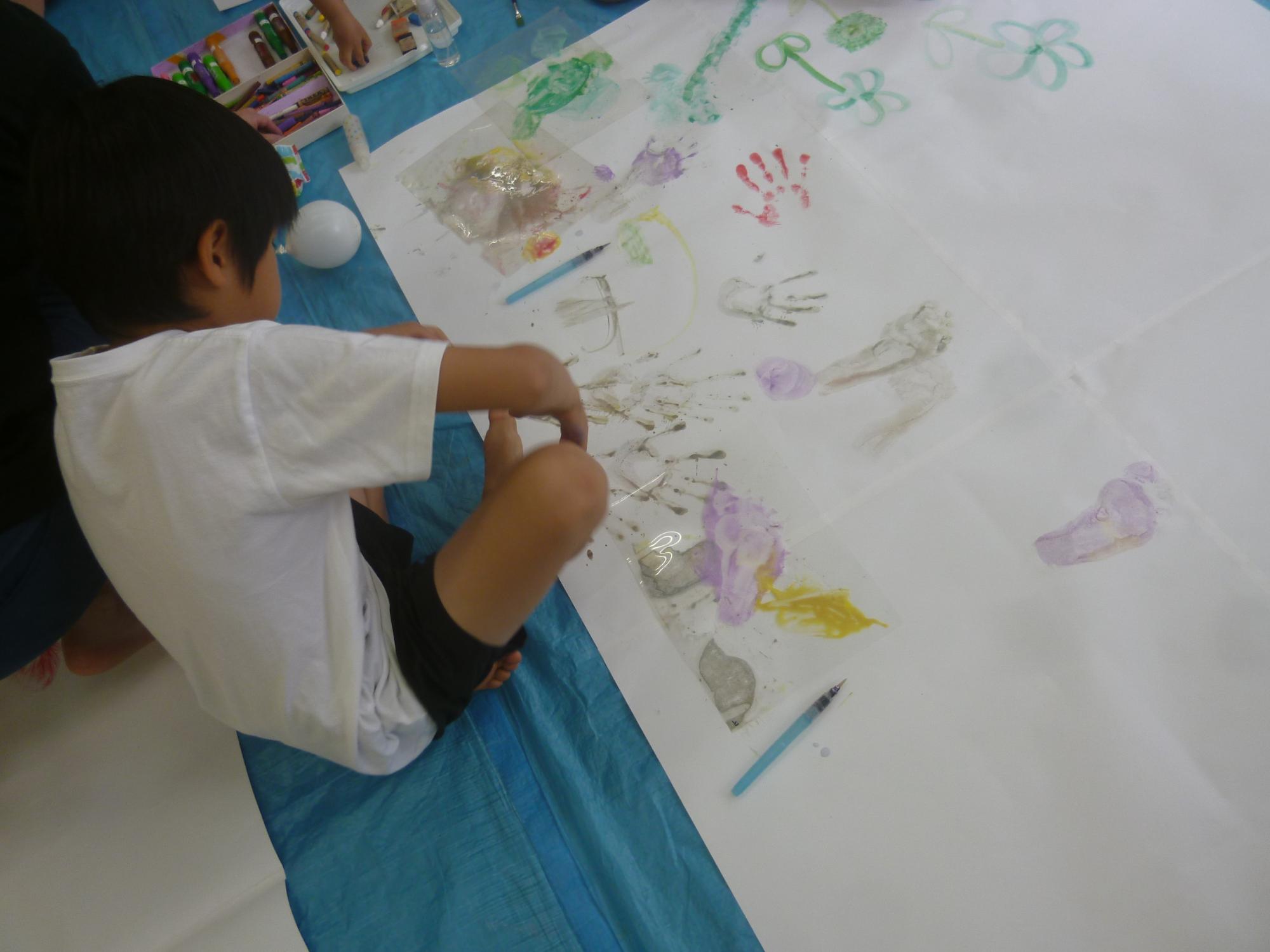「お絵描き広場」手形やスタンプを使い模様をつける小学生の写真