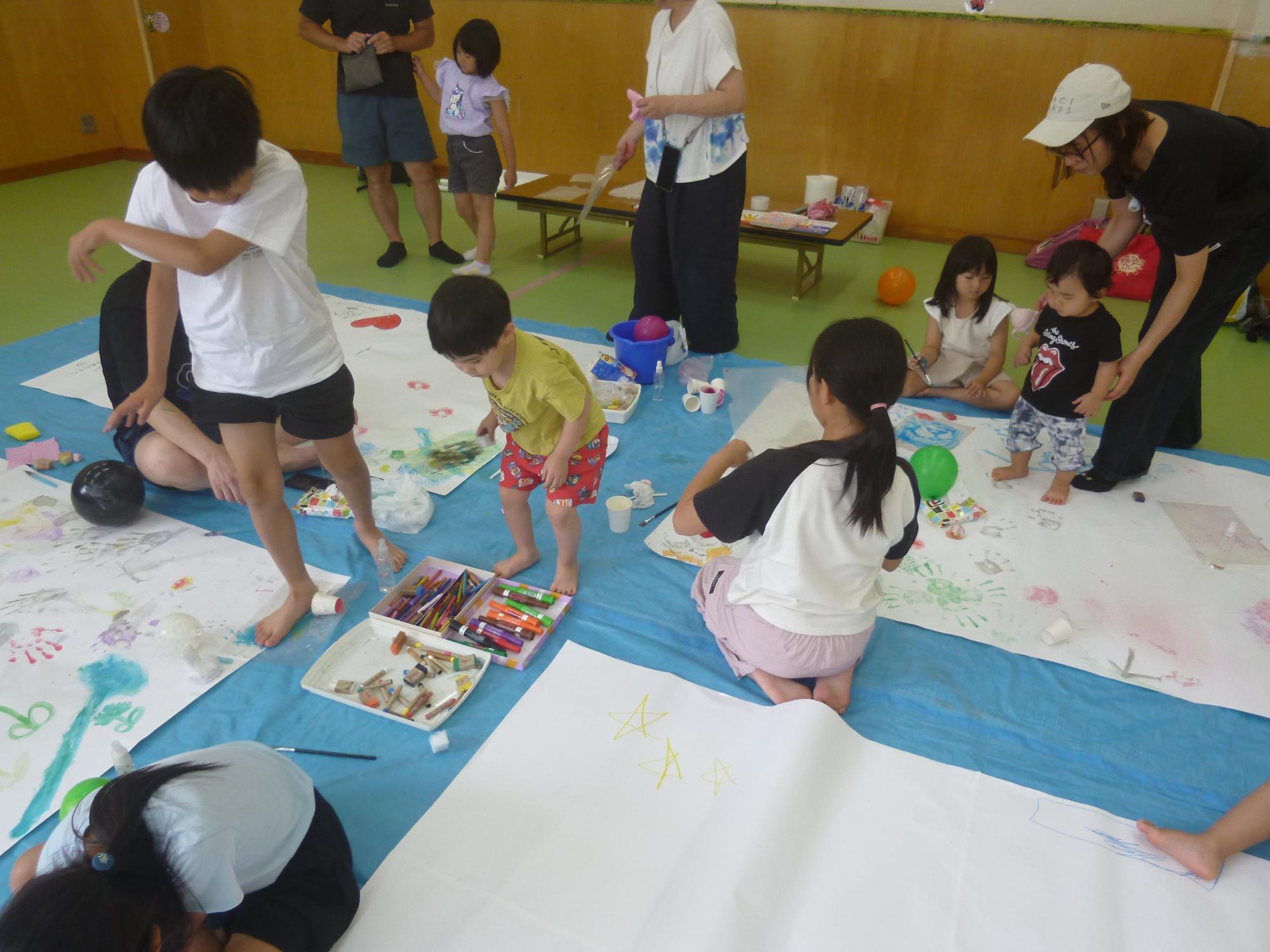 「お絵描き広場」集会室に紙を広げ、参加者全員が絵を描いている写真