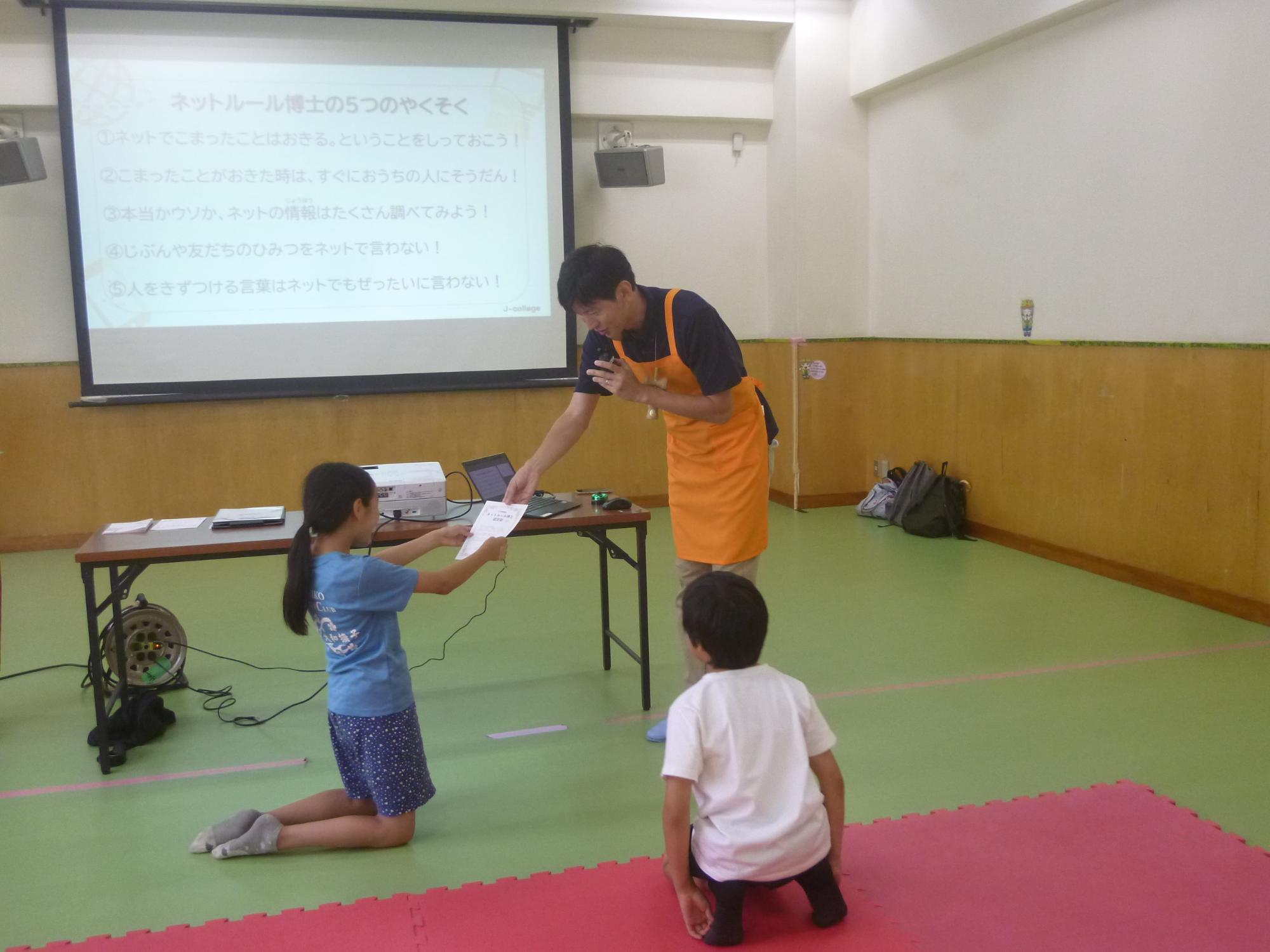 「ITリテラシー講座」、修了証を講師の方から受け取る小学生の写真