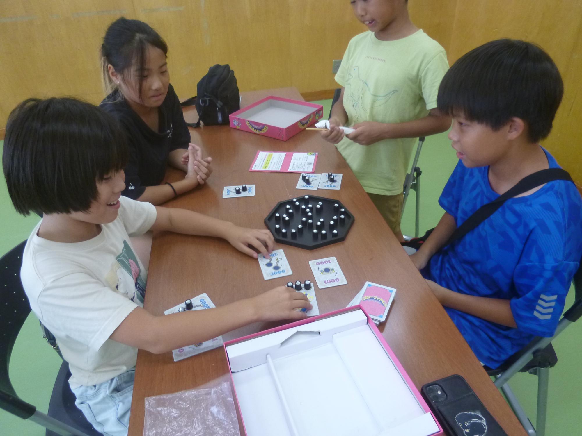 「ボードゲームで遊ぼう」4人でボードゲームを遊ぶ小学生の写真