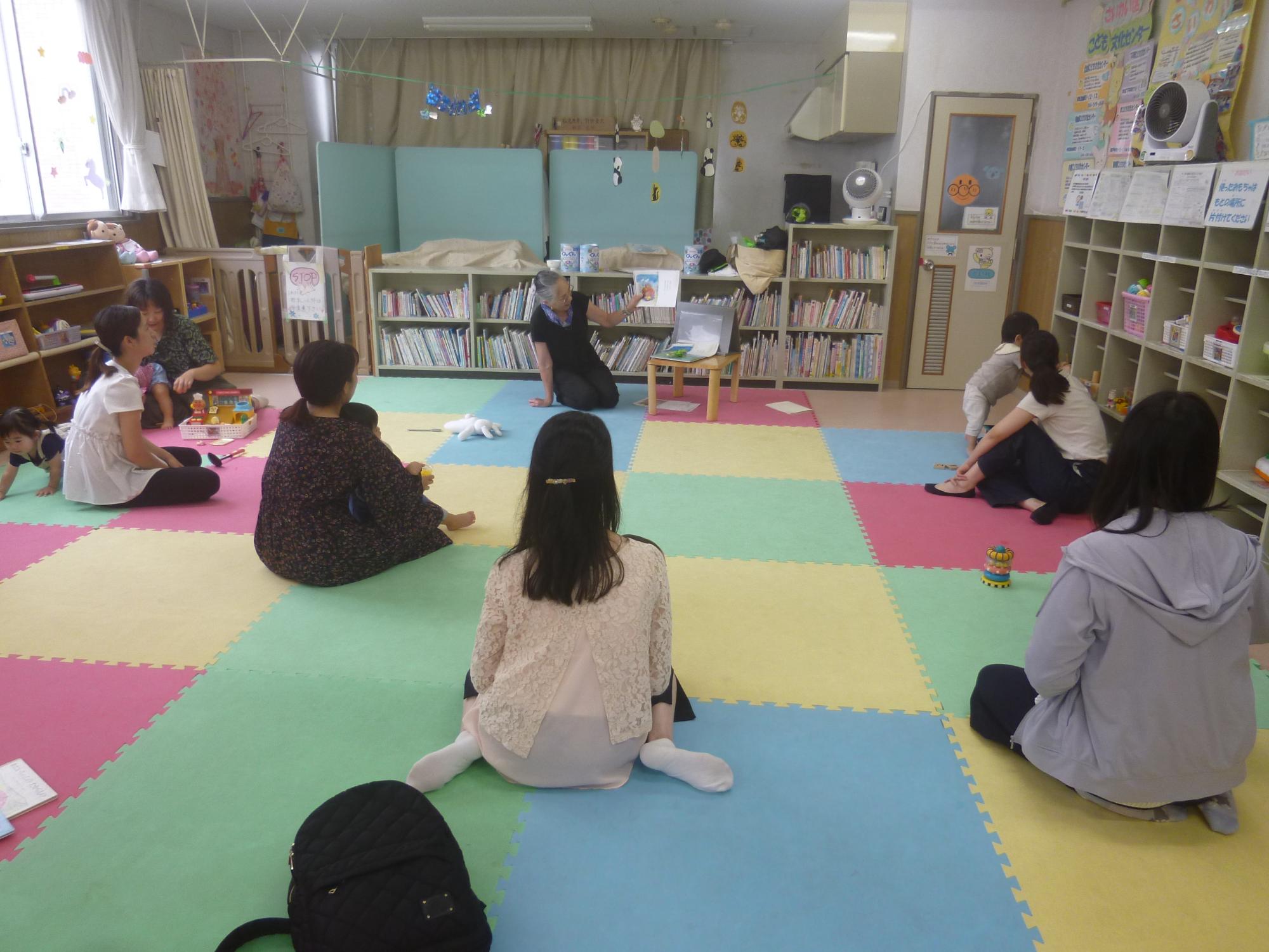 読み聞かせを聞く幼児親子の写真