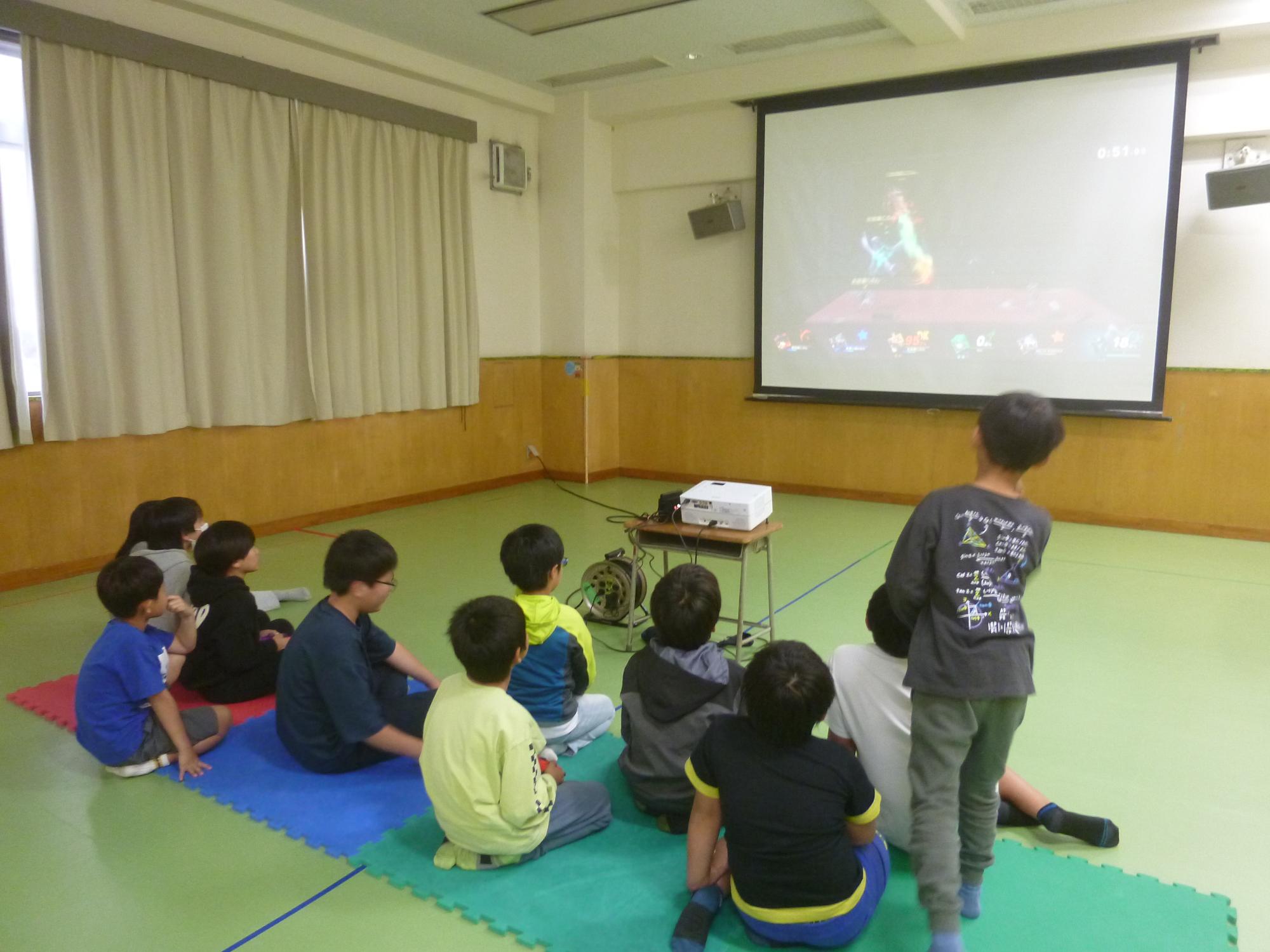 「eスポーツで遊ぼう」ゲームの前に座って盛り上がる小学生たちの写真