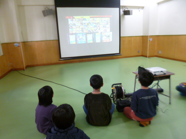 ゲーム画面を映したプロジェクターをみるこどもたちの写真