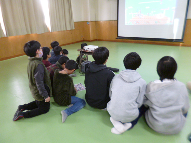 ゲーム画面を映したプロジェクターをみるこどもたちの写真
